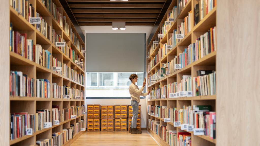 alt"ผู้หญิงเลือกอ่านหนังสือในชั้นวางหนังสือ"